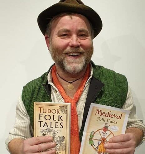 A man in a green jacket and hat holding two children's books