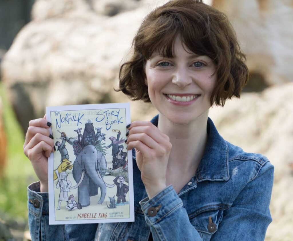 A lady smiling and holding her children's story book