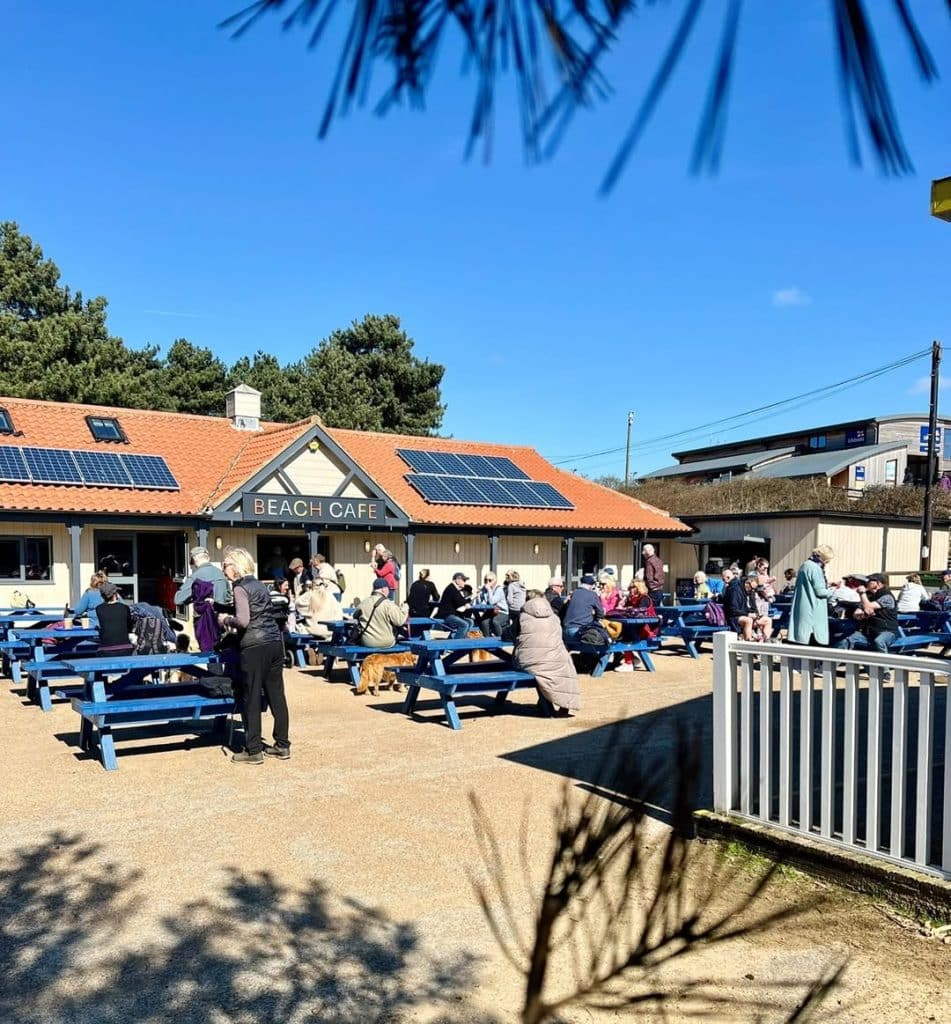 People enjoying a break and a bit to eat on the blue benches outside the Beach Café in Wells-Next-the-Sea