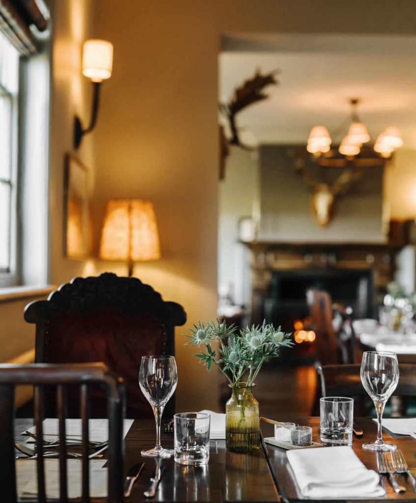 A cosy restaurant with a table set for a meal and a fire in the background.