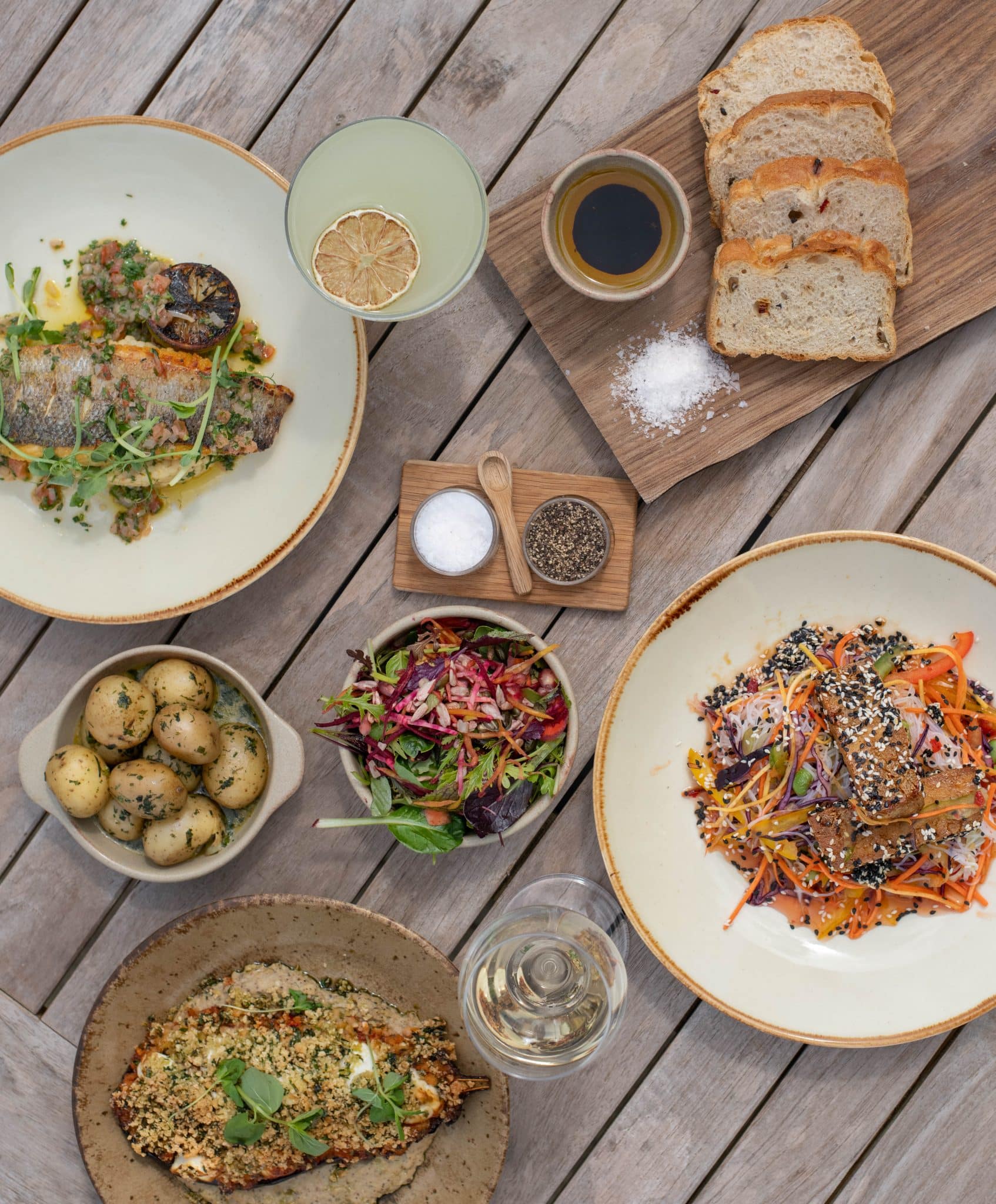 A variety of summery lunch dishes on a wooden table outside