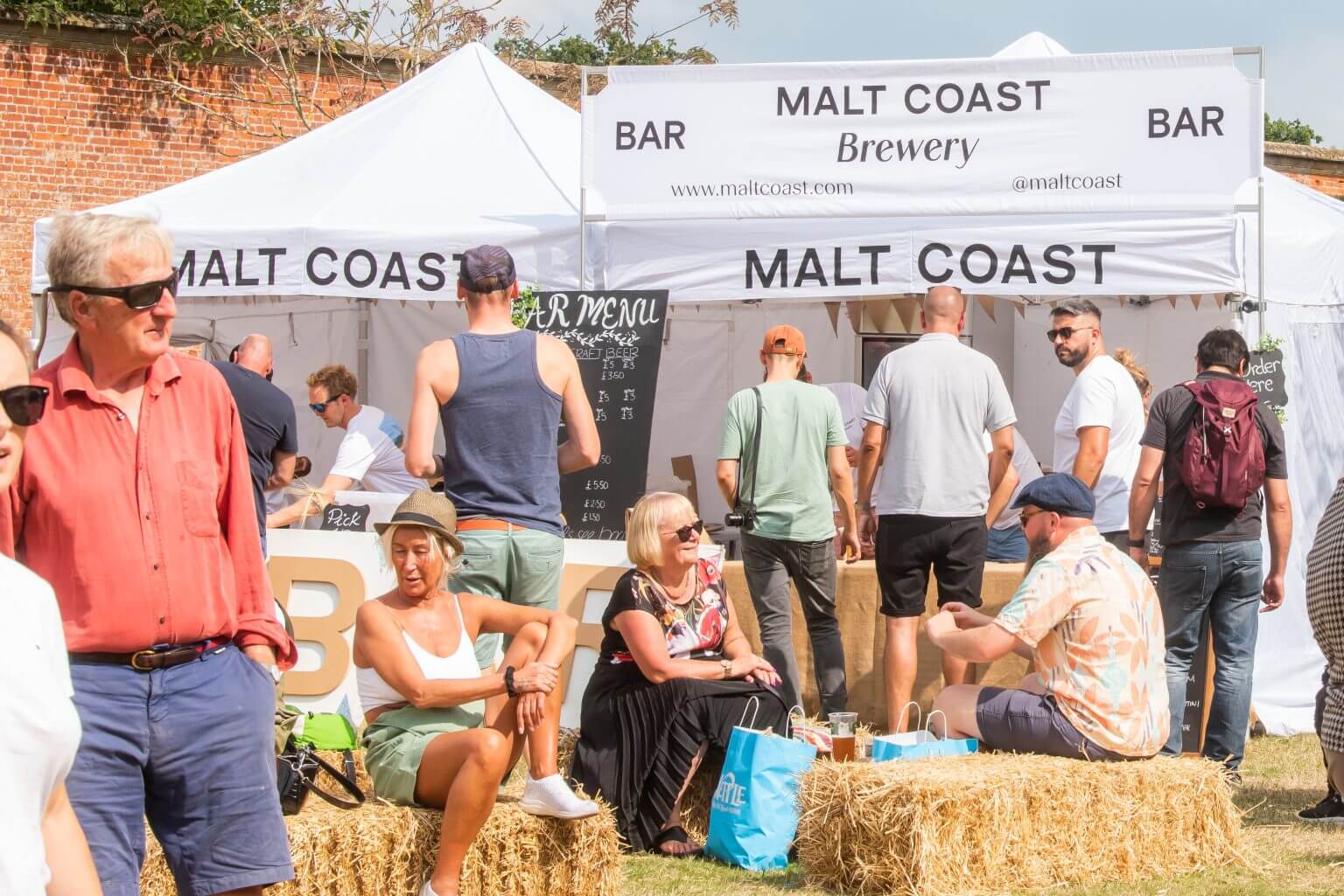 People relax on hay bales at North Norfolk Food & Drink Festival