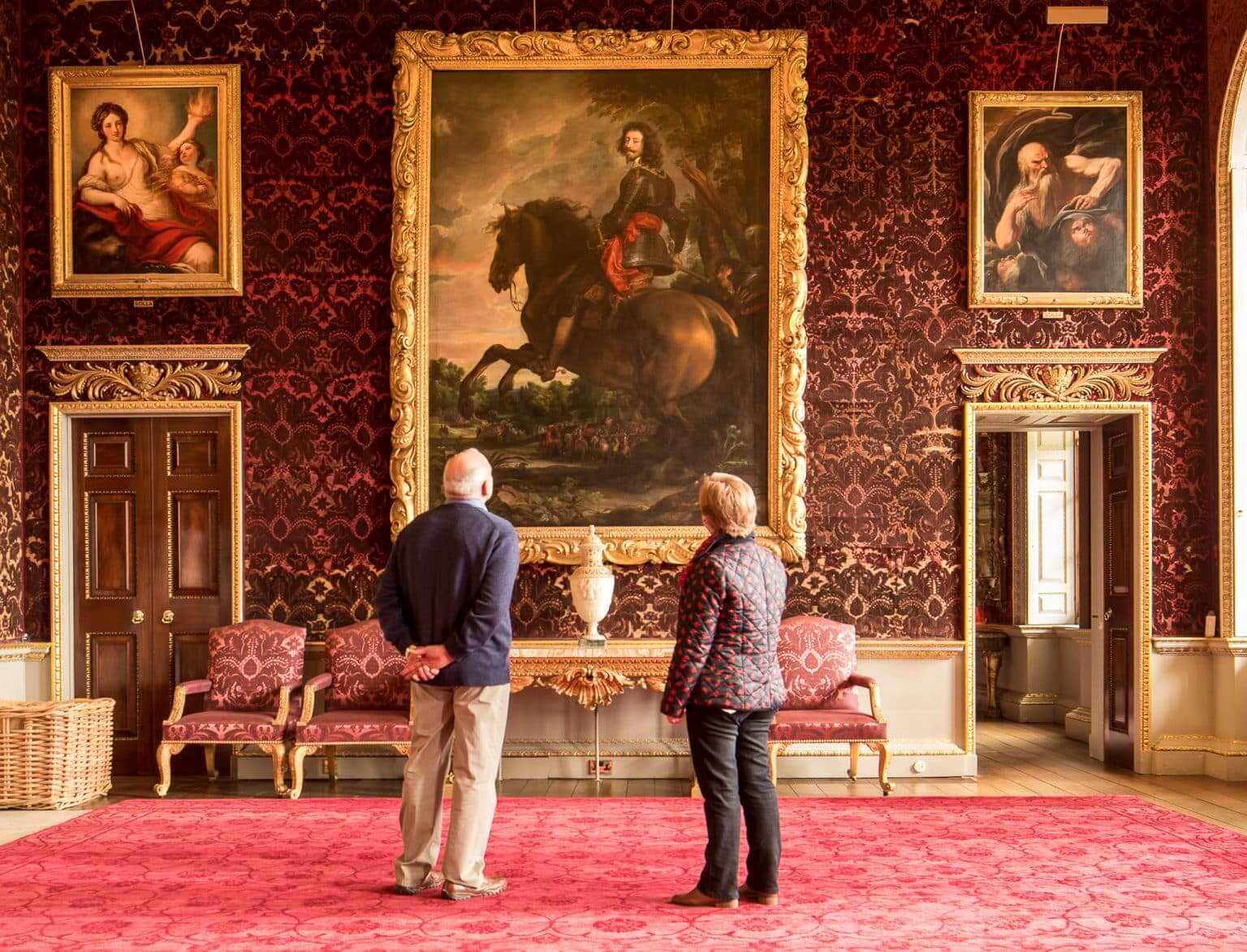 A man and women stare up at artwork in Holkham's Saloon
