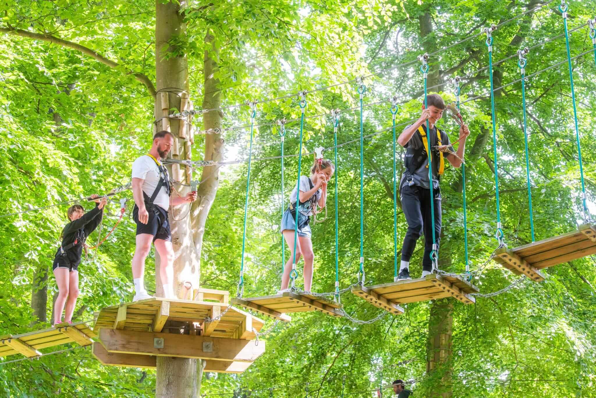 A family with harnesses on balance on the high ropes course