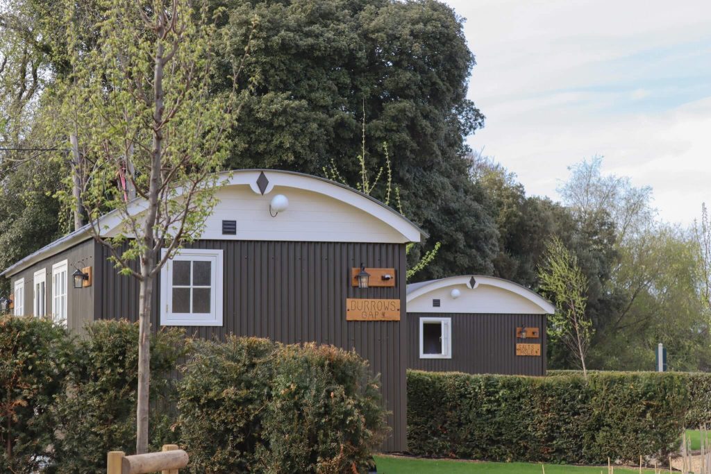 The exteriors of two shepherd huts surrounded by greenery