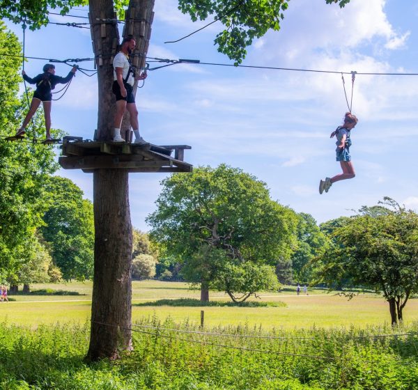 A girl zips on a zip wire on a summer day at the ropes course at Holkham