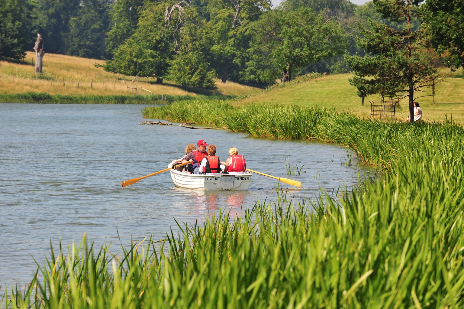 A group share a rowing boat and paddle on Holkham Lake