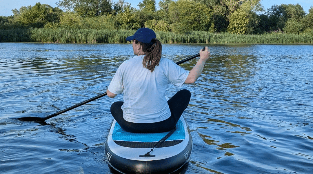 Woman sitting on a paddleboard in a Norfolk river