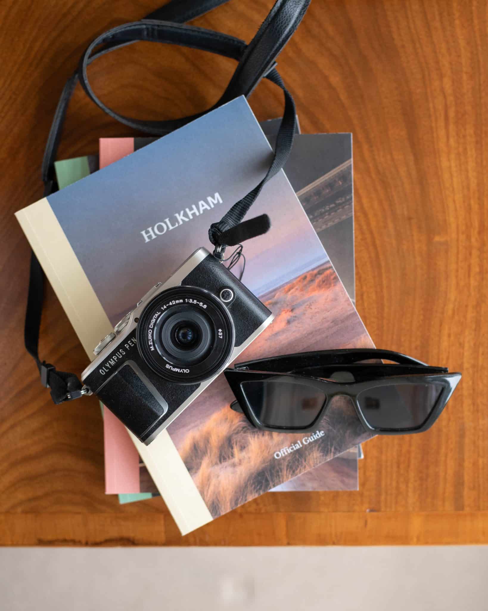 A camera and sunglasses sit on top of Holkham guidebooks