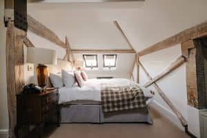 A bed in an attic room with sloping ceilings and beams.