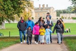 Family walk through Holkham Park with the Hall behind.