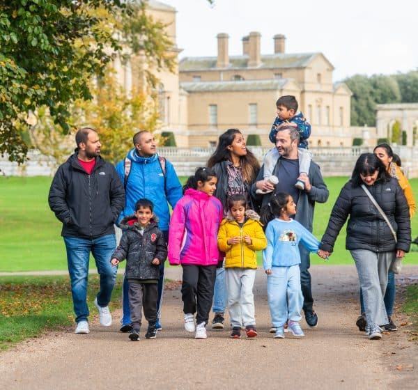 Family walk through Holkham Park with the Hall behind.