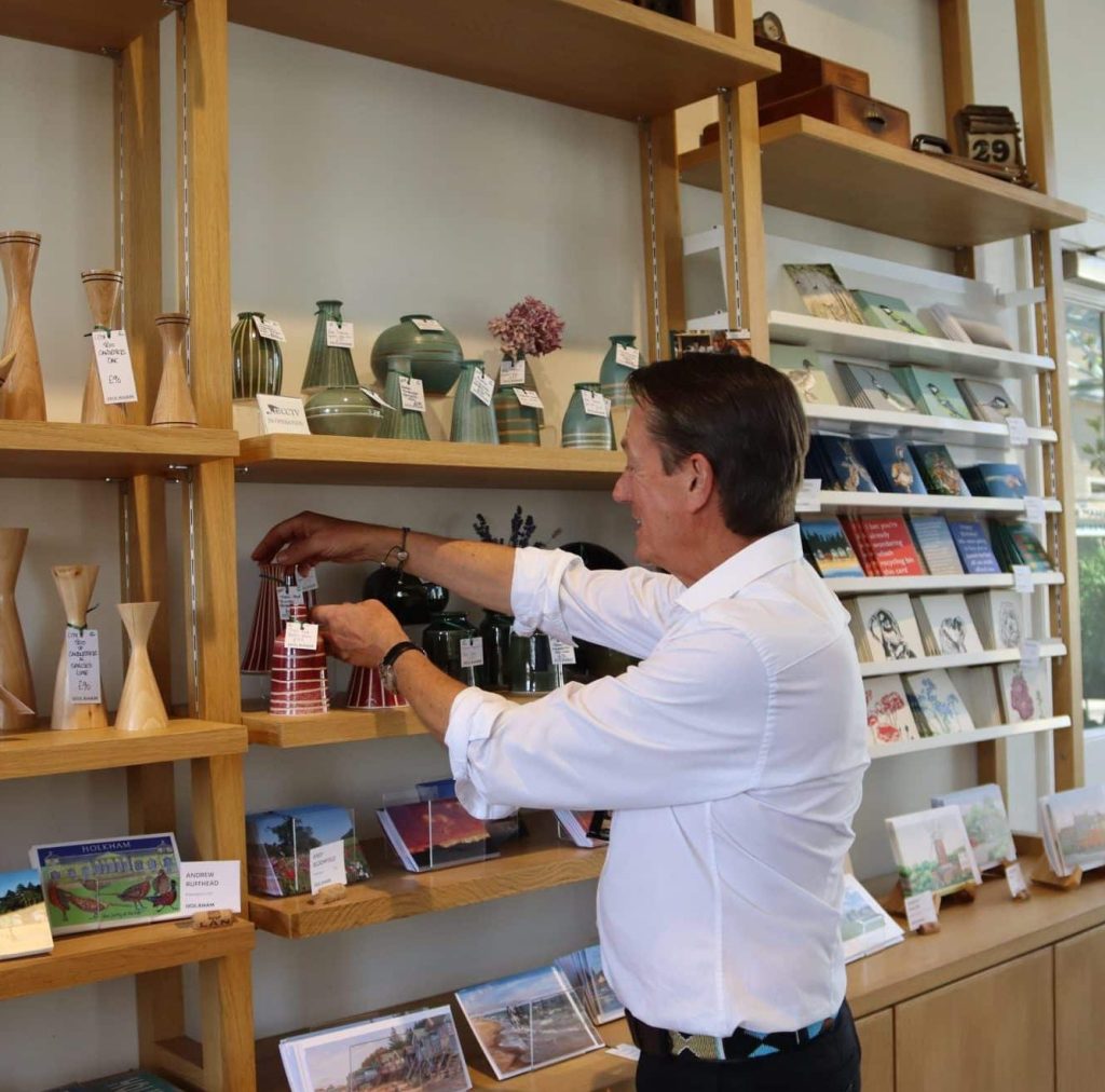 Kevin wearing a white shirt touching a pink vase