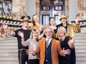 Dr Dance and Holkham team members stand with jazz hands on the Marble Hall stairs